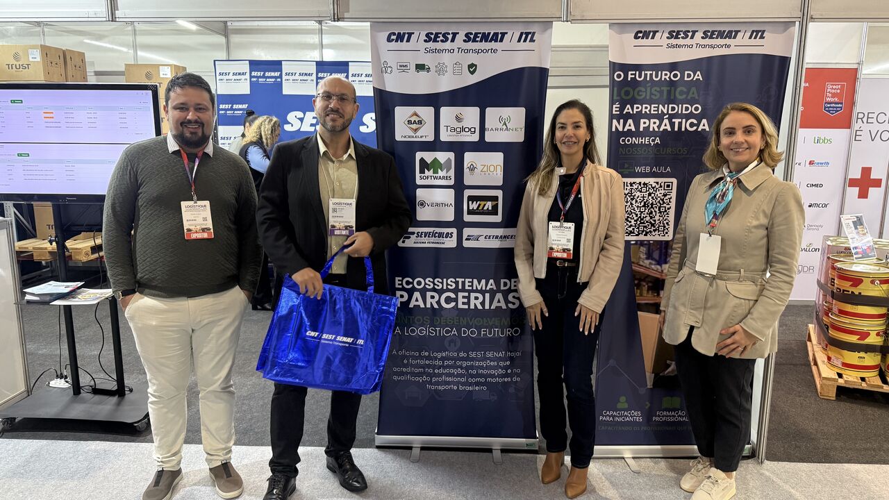 Quatro pessoas reunidas no estande da Logistique 2026, junto à estação de WMS e aos banners do SEST SENAT